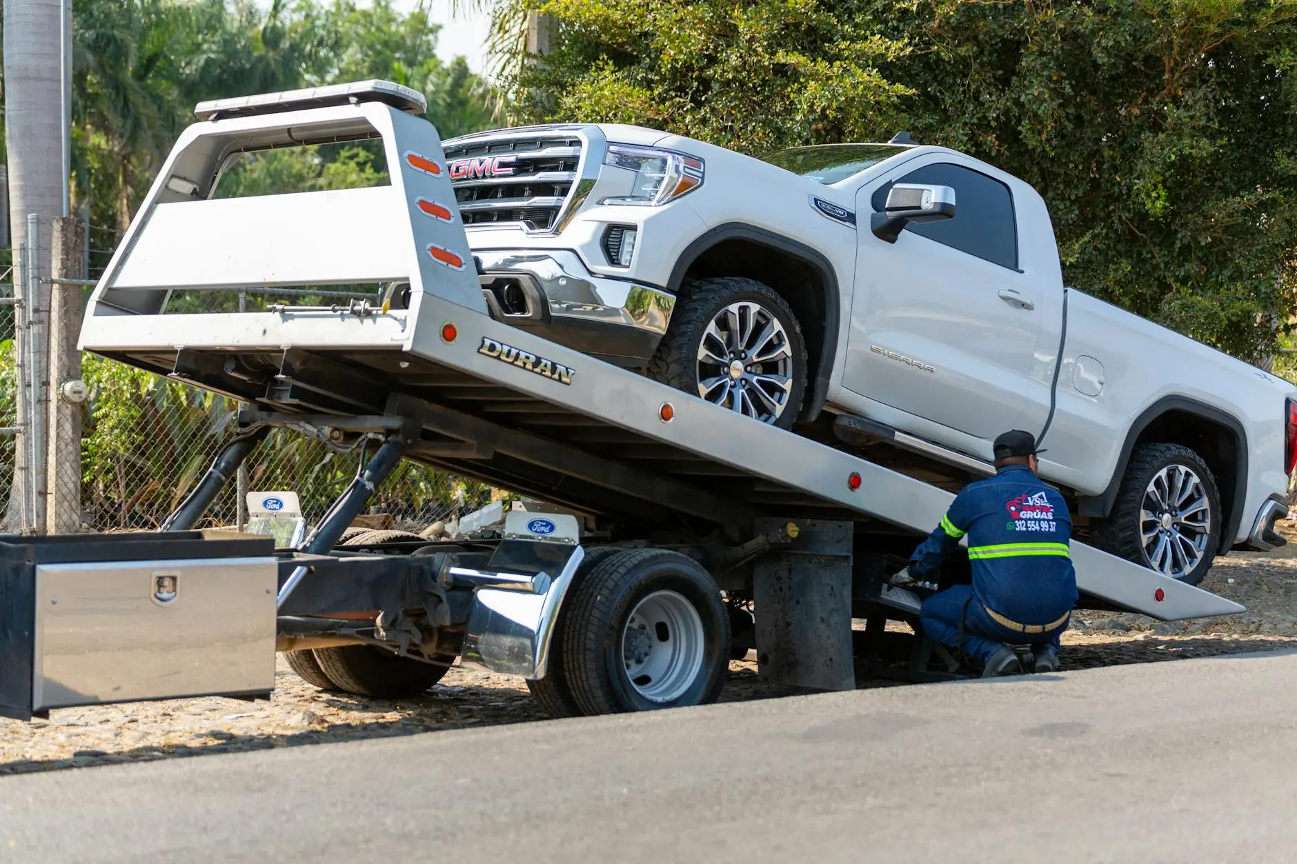A clean, modern flatbed tow truck parked safely on a Bensalem street with safety cones set up.
